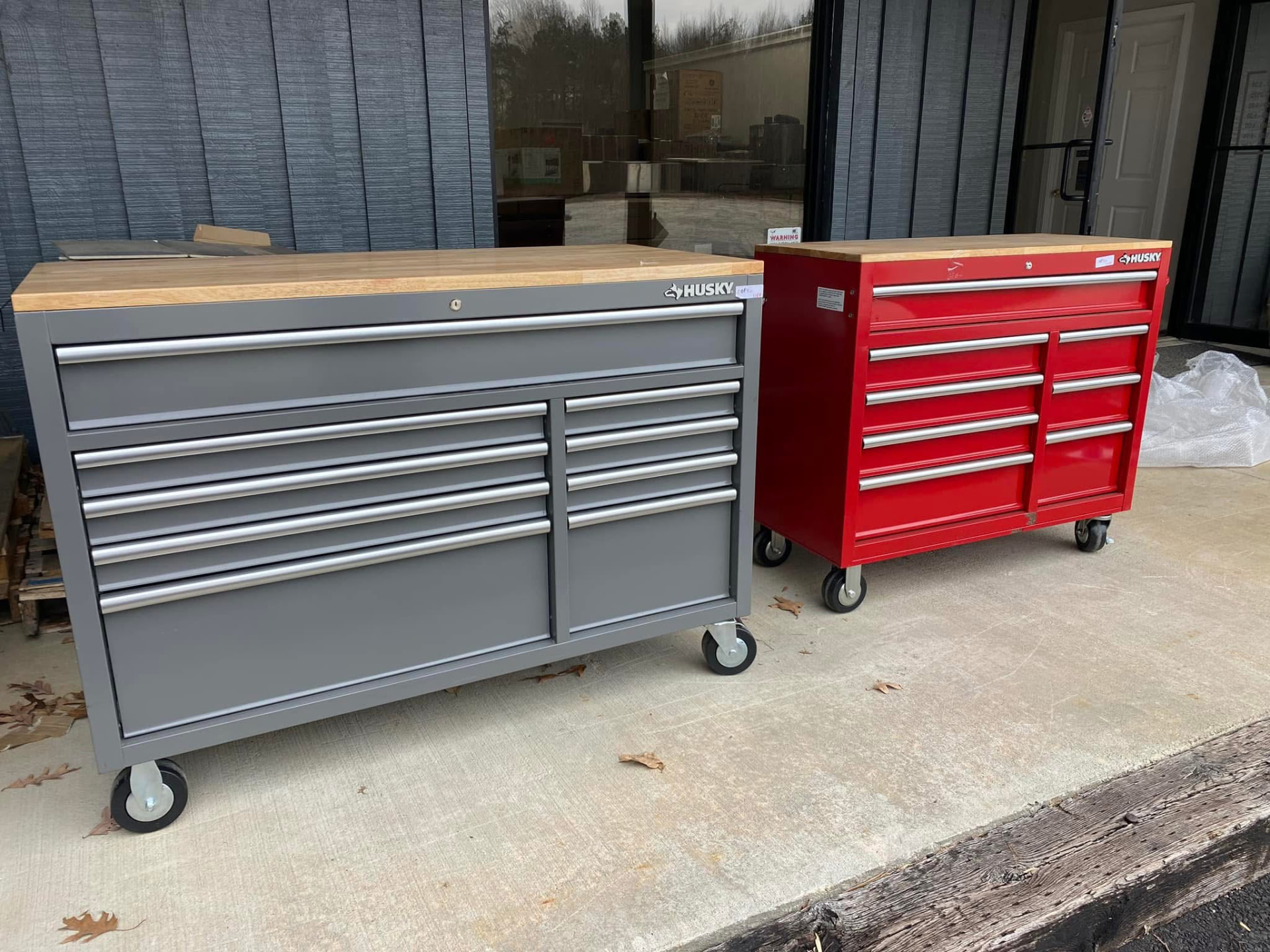 Grey and red Husky rolling tool chests with butcher block style wood tops outside the store