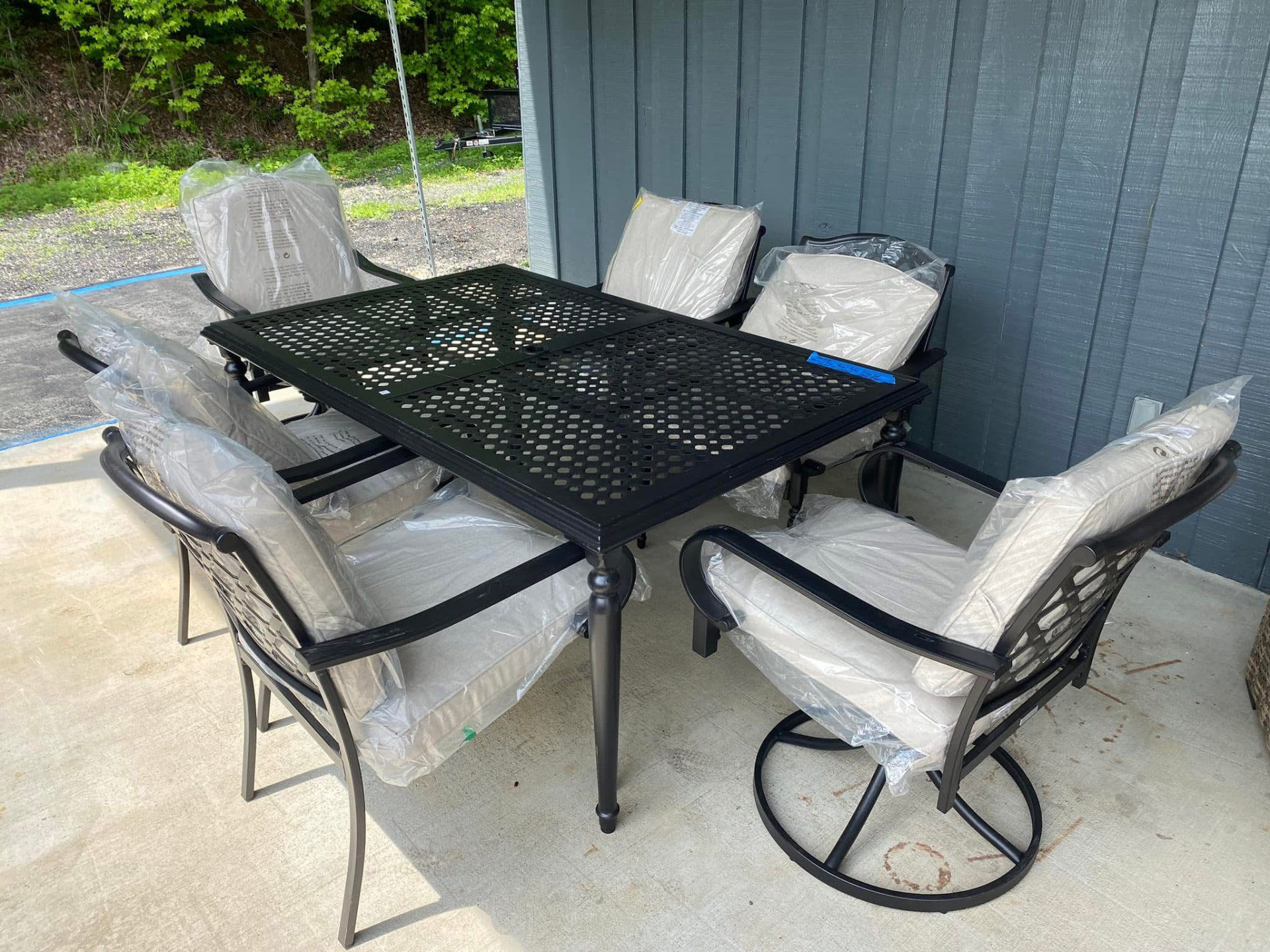 Black cast aluminum patio dining table with six cushioned chairs outside the store